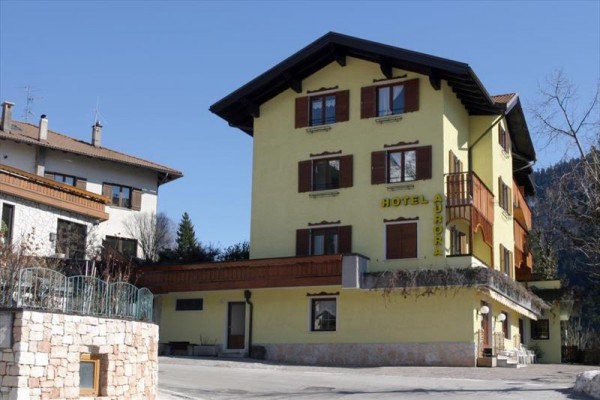 Trzypiętrowy budynek hotelu z drewnianymi okiennicami i balkonem.