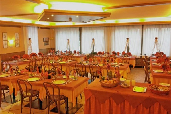 Restauracja z nakrytymi stołami i pomarańczowymi dekoracjami przygotowana na gości.