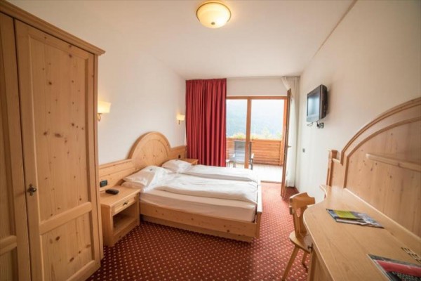 Pokój hotelowy z podwójnym łóżkiem, drewnianymi meblami i balkonem.