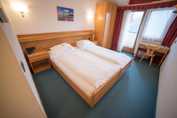 Pokój hotelowy z łóżkiem małżeńskim, biurkiem i balkonem.