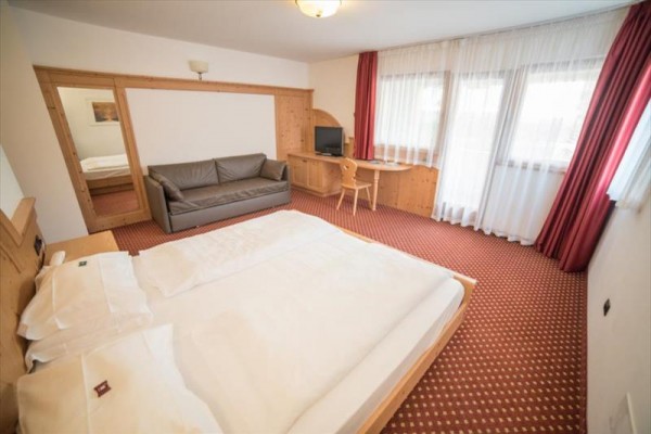 Pokój hotelowy z łóżkiem dwuosobowym, sofą, biurkiem i telewizorem.