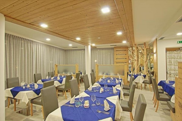 Restauracja z drewnianym sufitem, niebieskimi obrusami i szarymi krzesłami.