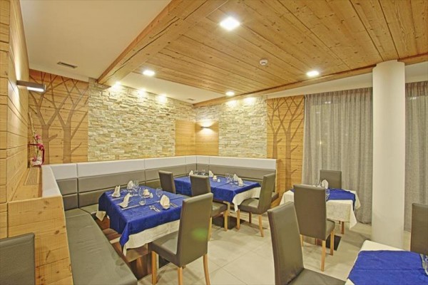 Nowoczesna restauracja z drewnianymi panelami i przygotowanymi stolikami z niebieskimi obrusami.