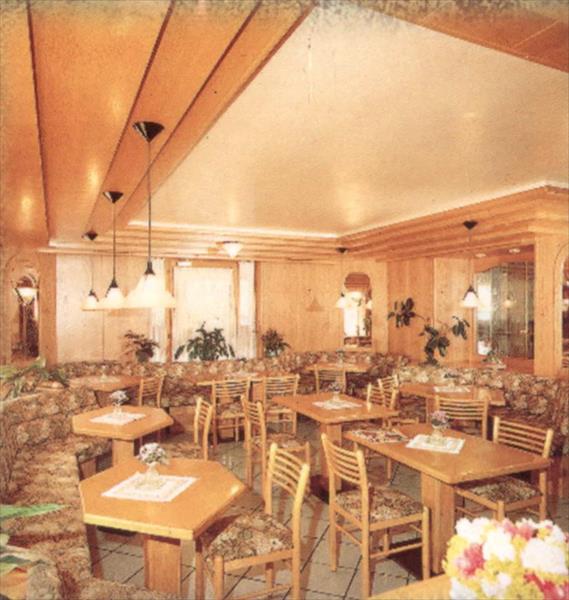 Restauracja z drewnianym wnętrzem, stołami, krzesłami i kwiatami.