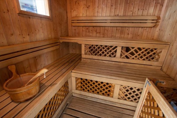 Drewniana sauna z ławkami i wiadrem.