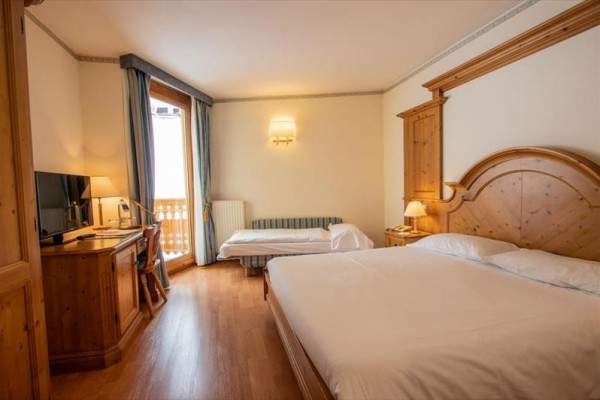 Pokój hotelowy z łóżkiem małżeńskim, biurkiem i telewizorem przy balkonie.