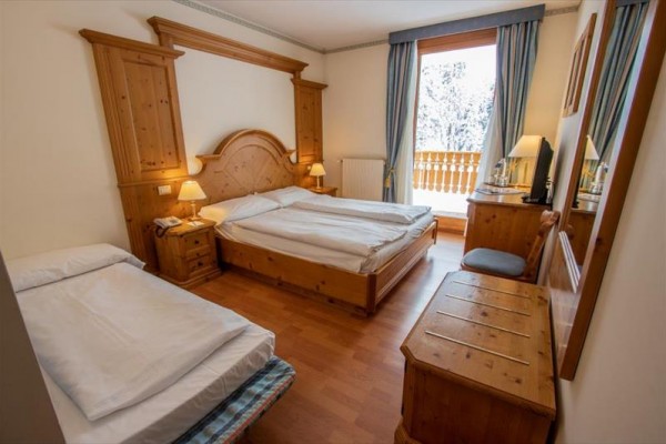 Pokój hotelowy z drewnianymi meblami i widokiem na ośnieżony balkon.