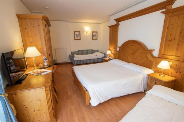 Pokój hotelowy z łóżkiem małżeńskim, sofą i drewnianymi meblami.