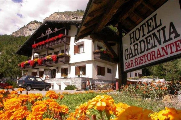 Hotel Gardenia z kwiatową dekoracją i górską scenerią w tle.