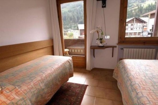 Pokój z dwoma pojedynczymi łóżkami i balkonem z widokiem na góry.