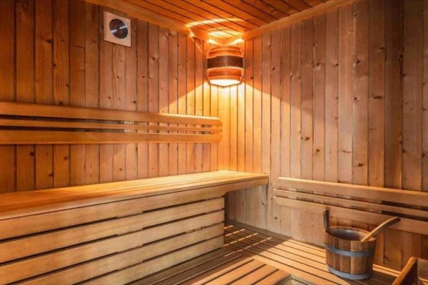Sauna z drewnianymi ławkami i wiadrem na wodę.