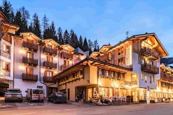 Malowniczy górski hotel o zmierzchu z jasnymi oknami i drewnianymi balkonami.