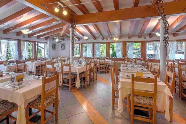 Restauracja z drewnianymi stołami i krzesłami, nakrytymi stołami i dużymi oknami.