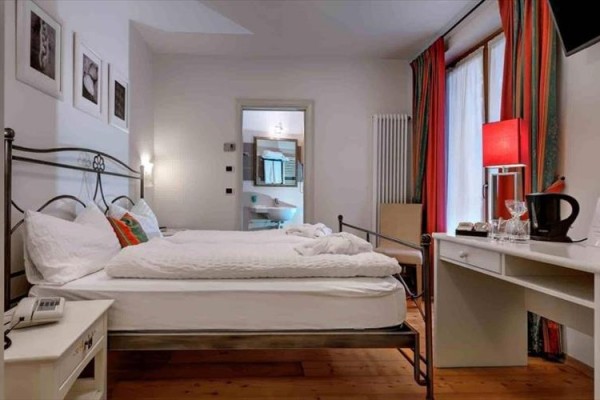 Elegancki pokój hotelowy z łóżkiem dwuosobowym, biurkiem i przylegającą łazienką.
