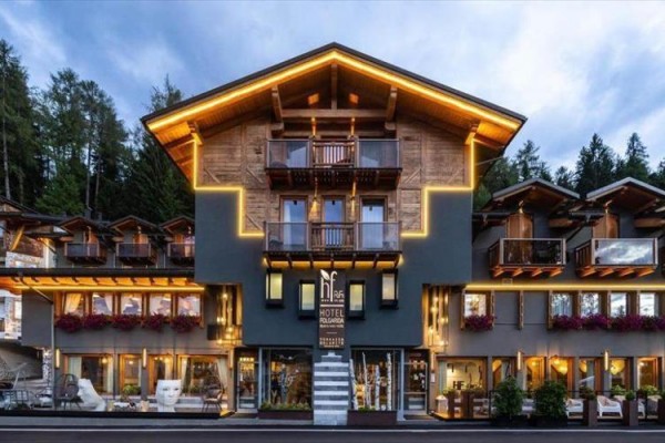 Nowoczesny górski hotel z drewnianym wykończeniem i oświetleniem, otoczony lasem.