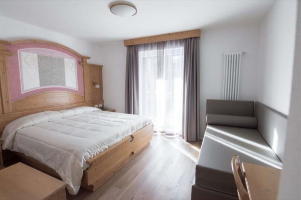 Nowoczesny alpejski hotel z drewnianą elewacją i przeszklonym wejściem.
