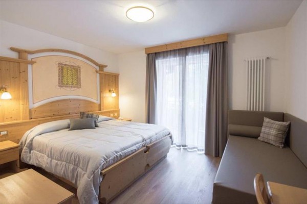 Nowoczesny drewniany hotel z balkonami i drzewami na pierwszym planie.