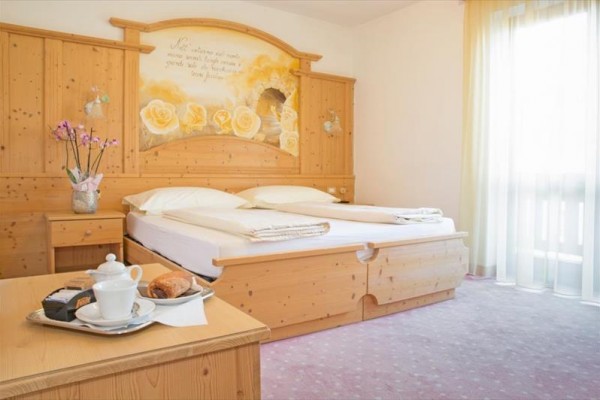 Pokój hotelowy z drewnianymi meblami, podwójnym łóżkiem, rozkładaną kanapą i telewizorem.