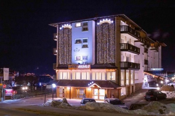Hotel oświetlony nocą z świątecznymi lampkami na fasadzie.