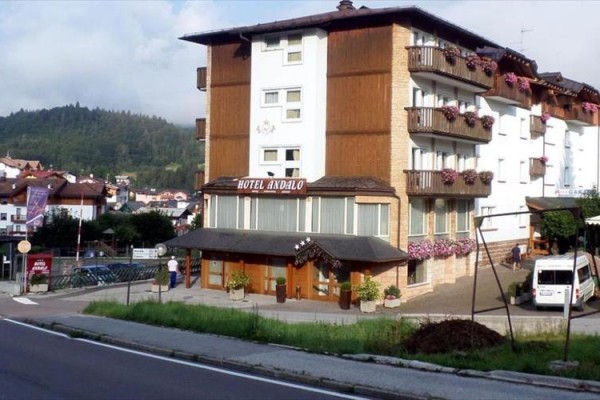 Hotel Andalo z kwiatami na balkonach i górami w tle.