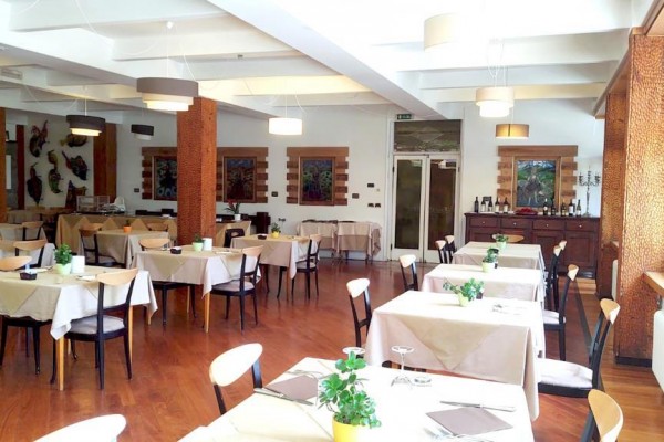 Jasna restauracja z drewnianą podłogą i stolikami gotowymi do serwowania.