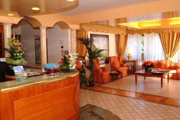 Recepcja hotelowa z kwiatami, sofami i stolikiem konferencyjnym.