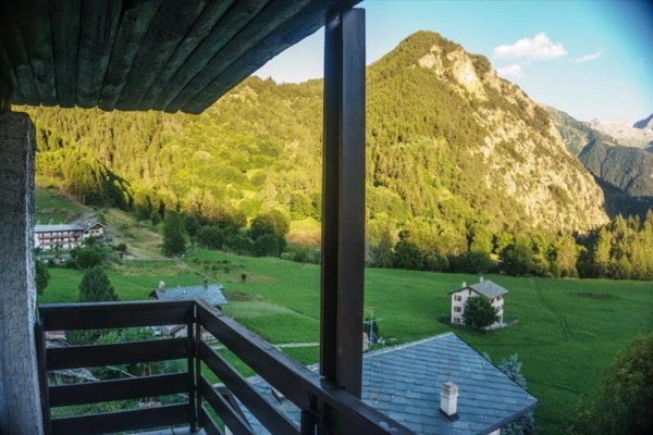 Widok z balkonu na górski krajobraz z lasami i łąkami.