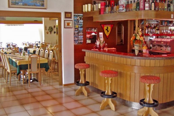Wnętrze restauracji z drewnianym barem i sąsiednią jadalnią z nakrytymi stołami.