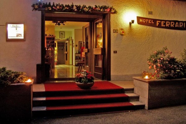 Wejście do hotelu z czerwonym dywanem i kwiatowymi dekoracjami.