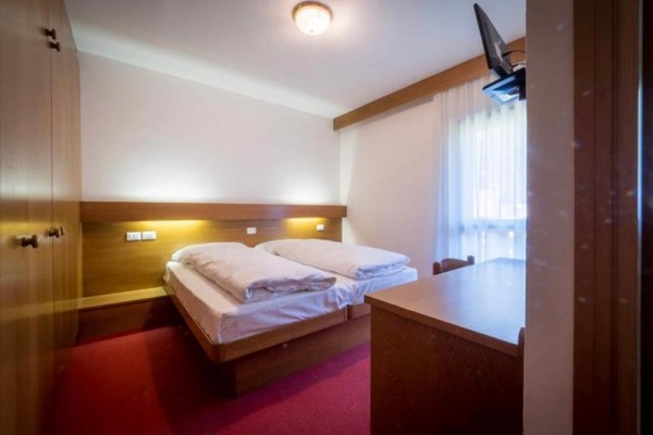 Sypialnia z łóżkiem małżeńskim, lampkami nocnymi, telewizorem i stolikiem.