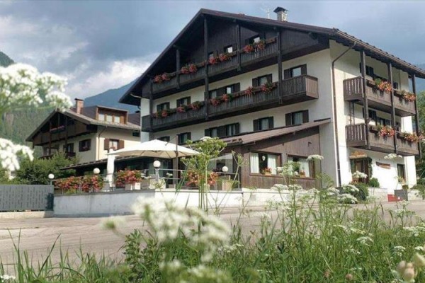 Górski hotel z drewnianymi balkonami i kwiatową dekoracją przy oknach.