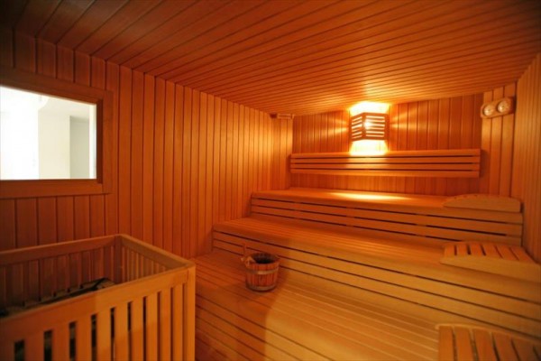 Drewniana sauna z ławkami i wiadrem na wodę.