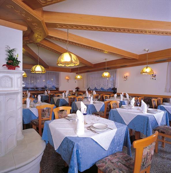 Restauracja z drewnianym sufitem i stołami z niebiesko-białymi obrusami oraz przygotowaną zastawą.