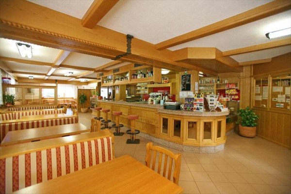 Wnętrze restauracji z drewnianymi ławkami i barem.