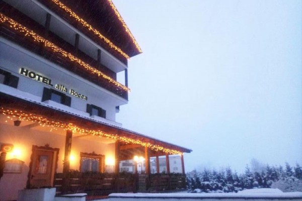 Ośnieżony budynek hotelu ozdobiony świątecznymi światłami.
