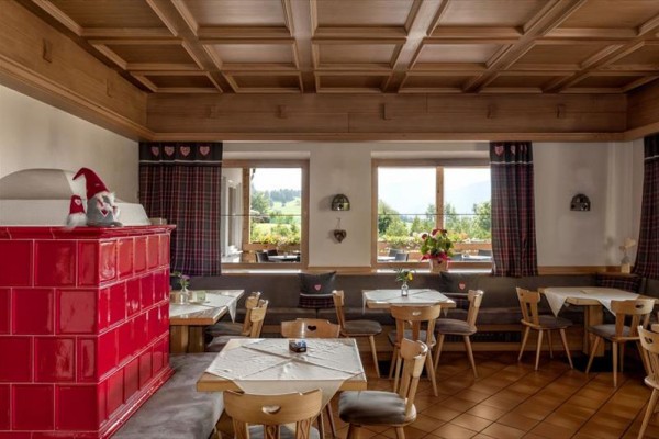 Tradycyjne wnętrze restauracji z drewnianą boazerią i czerwonym piecem kaflowym.