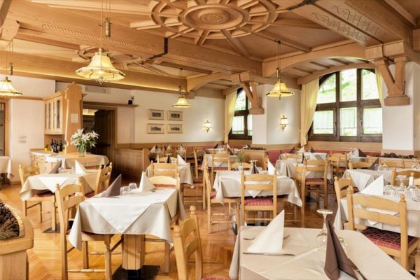 Elegancka restauracja z drewnianym sufitem i nakrytymi stołami.