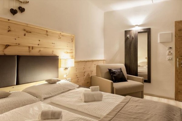 Nowoczesny pokój hotelowy z dwoma łóżkami i fotelem.