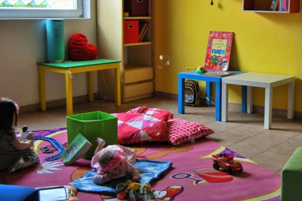 Kolorowa sala zabaw dla dzieci z zabawkami i książkami na dywanie.