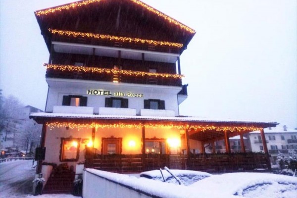Hotel z lampkami świątecznymi pokryty śniegiem.