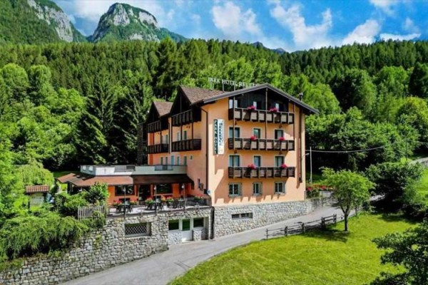 Hotel otoczony lasami i górami z niebieskim niebem w tle.