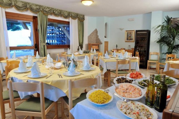 Restauracja z okrągłymi stolami przygotowanymi do posiłku i bufetowym stołem z różnorodnymi potrawami.