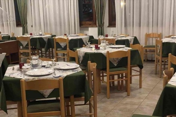 Restauracja z białymi i zielonymi obrusami na stołach przygotowana na kolację.