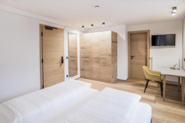 Nowoczesny pokój hotelowy z drewnianymi meblami, podwójnym łóżkiem i biurkiem.