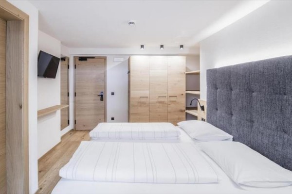 Nowoczesny pokój hotelowy z łóżkiem małżeńskim i drewnianymi meblami.