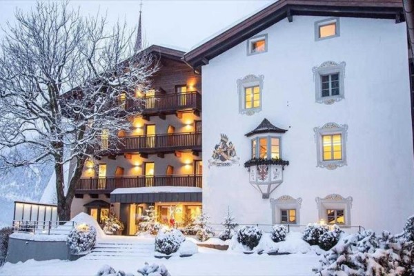 Ośnieżony hotel o zachodzie słońca z zapalonymi światłami w oknach.