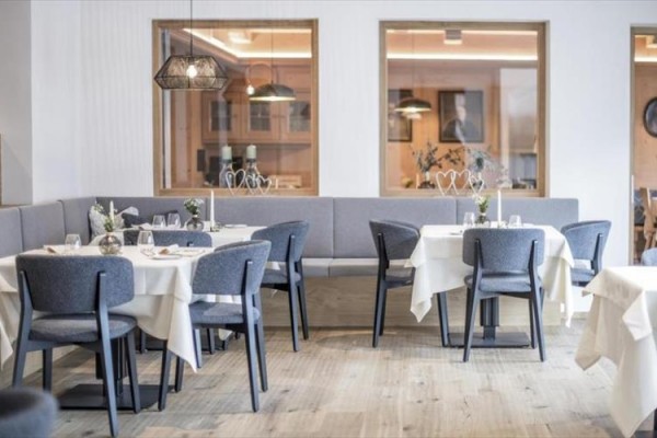 Elegancka restauracja z szarymi krzesłami i białymi obrusami.
