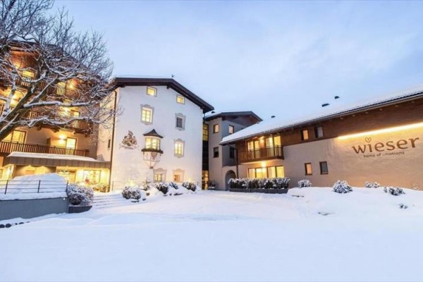 Ośnieżony kompleks hotelowy z zapalonymi oknami o zmierzchu.