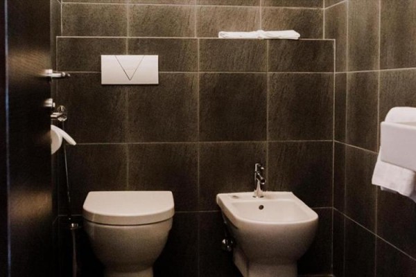 Toaleta i bidet w ciemnej łazience z kafelkami.