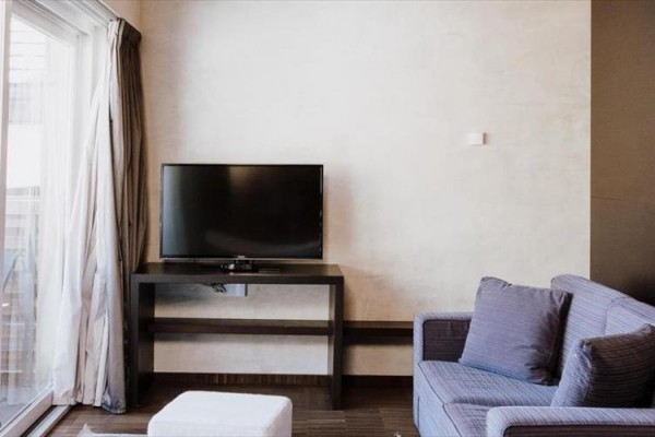 Nowoczesny salon z telewizorem na stole, sofą i dużym oknem.